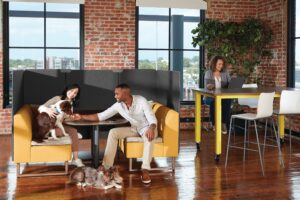 dogs at a pet friendly workplace make everybody smile in an office with a huddle area booth and tall working desk